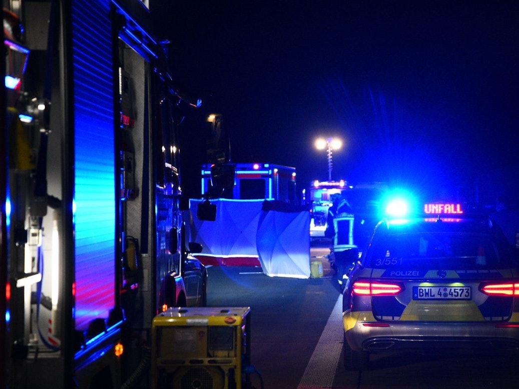 Einsatzfahrzeuge von Polizei und Feuerwehr stehen mit Blaulicht an der Unfallstelle.