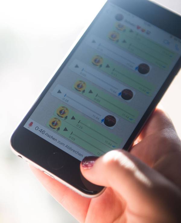 Eine Frau spricht eine Sprachnachricht in ein Smartphone und nutzt dafür den Messangerdienst Whatsapp.