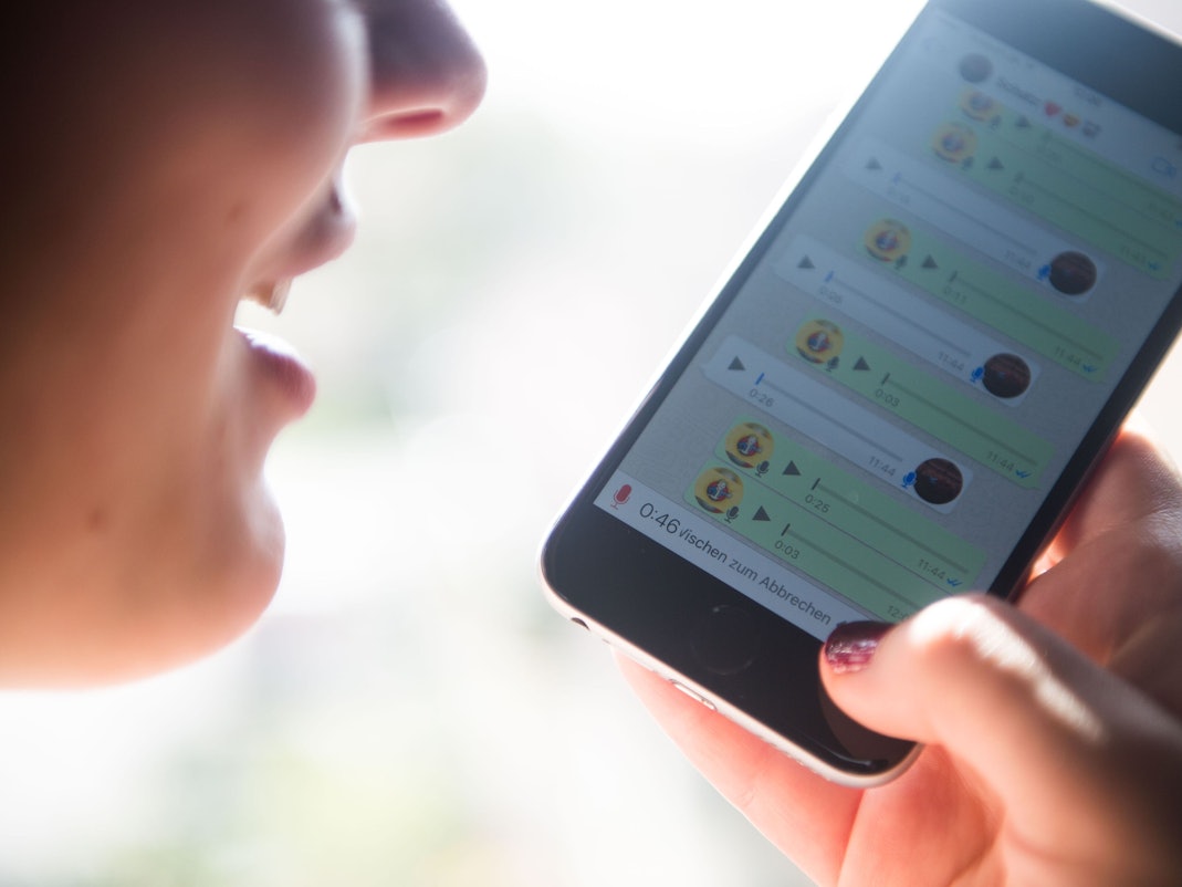 Eine Frau spricht eine Sprachnachricht in ein Smartphone und nutzt dafür den Messangerdienst Whatsapp.
