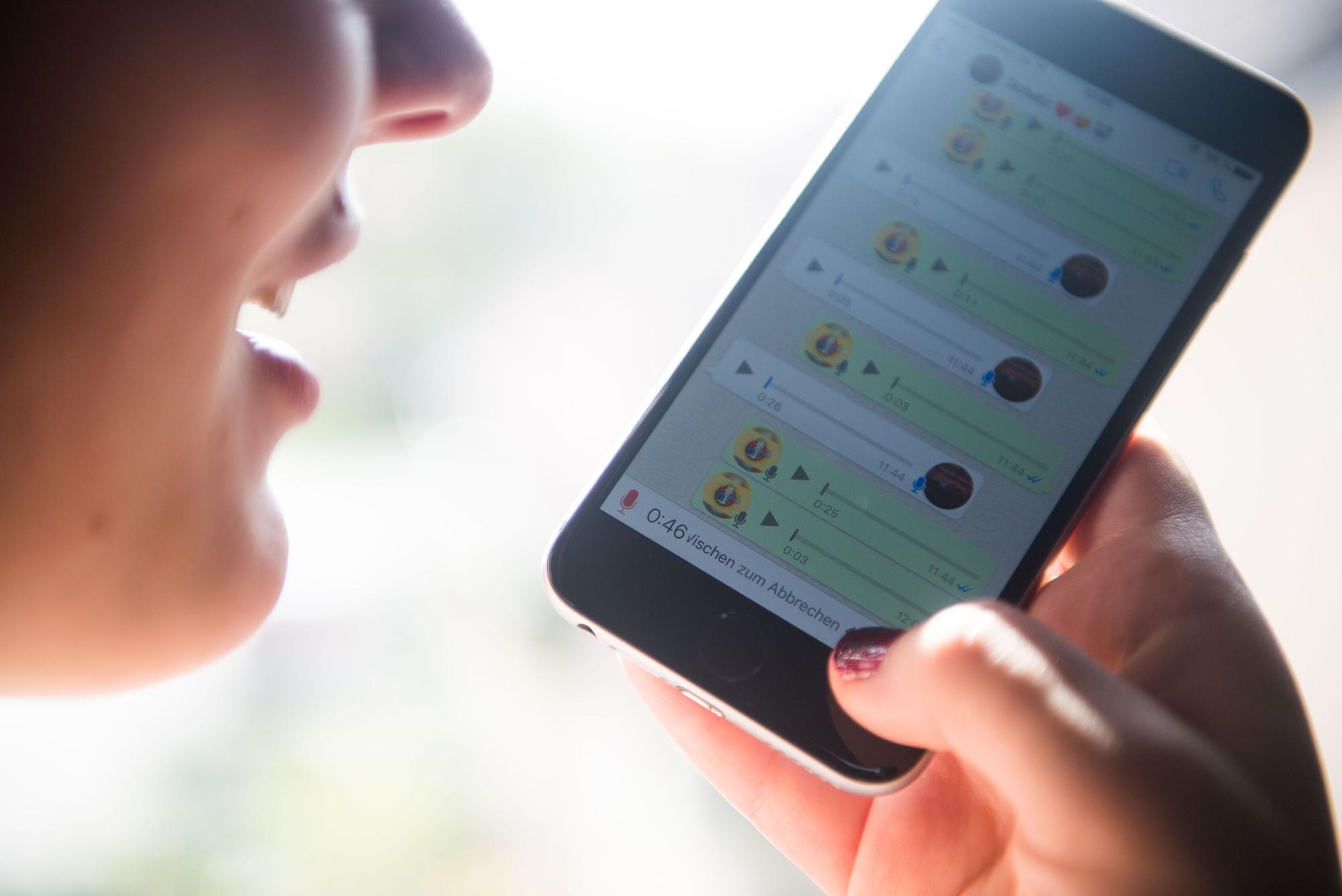 Eine Frau spricht eine Sprachnachricht in ein Smartphone und nutzt dafür den Messangerdienst Whatsapp.