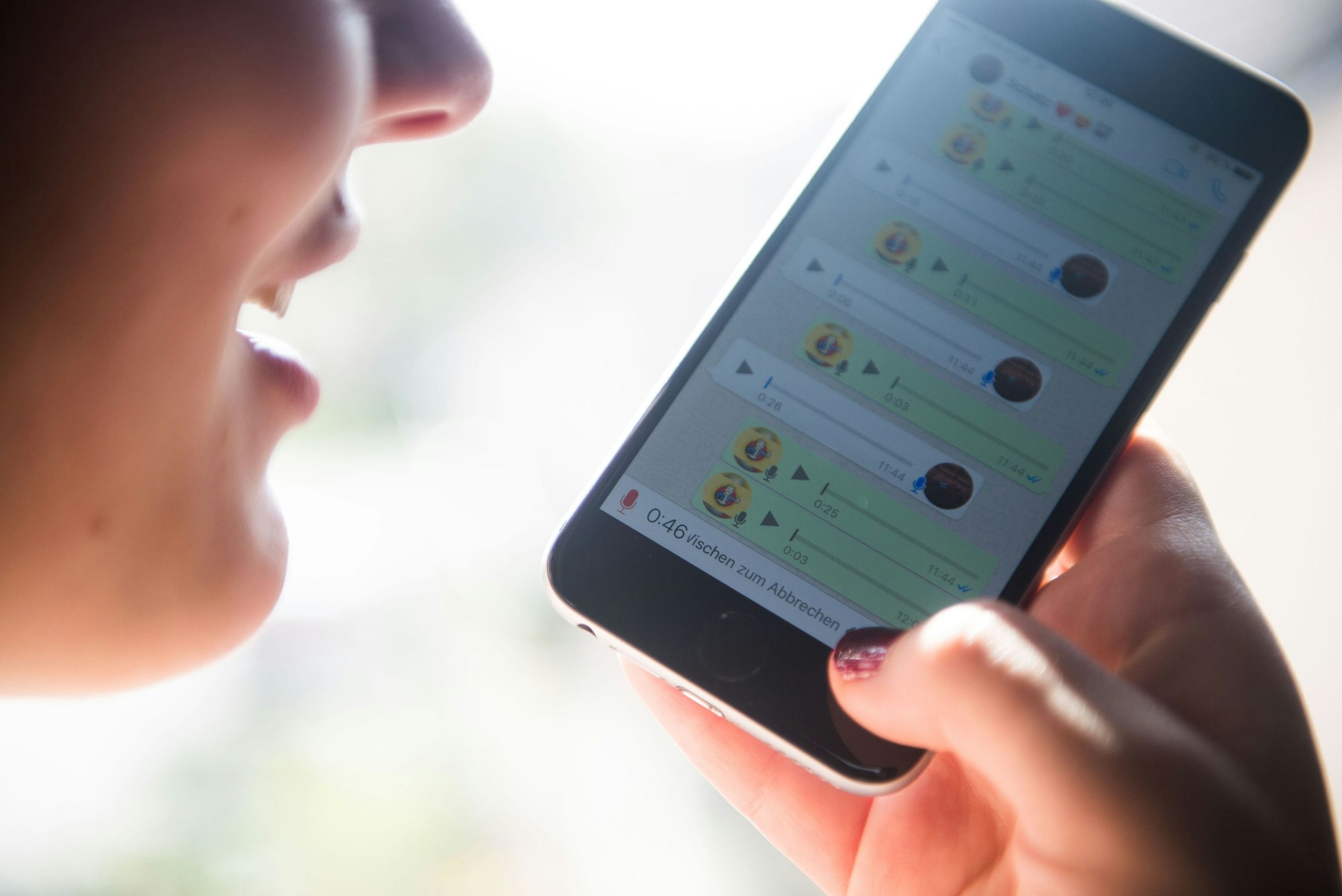 Eine Frau spricht eine Sprachnachricht in ein Smartphone und nutzt dafür den Messangerdienst Whatsapp.