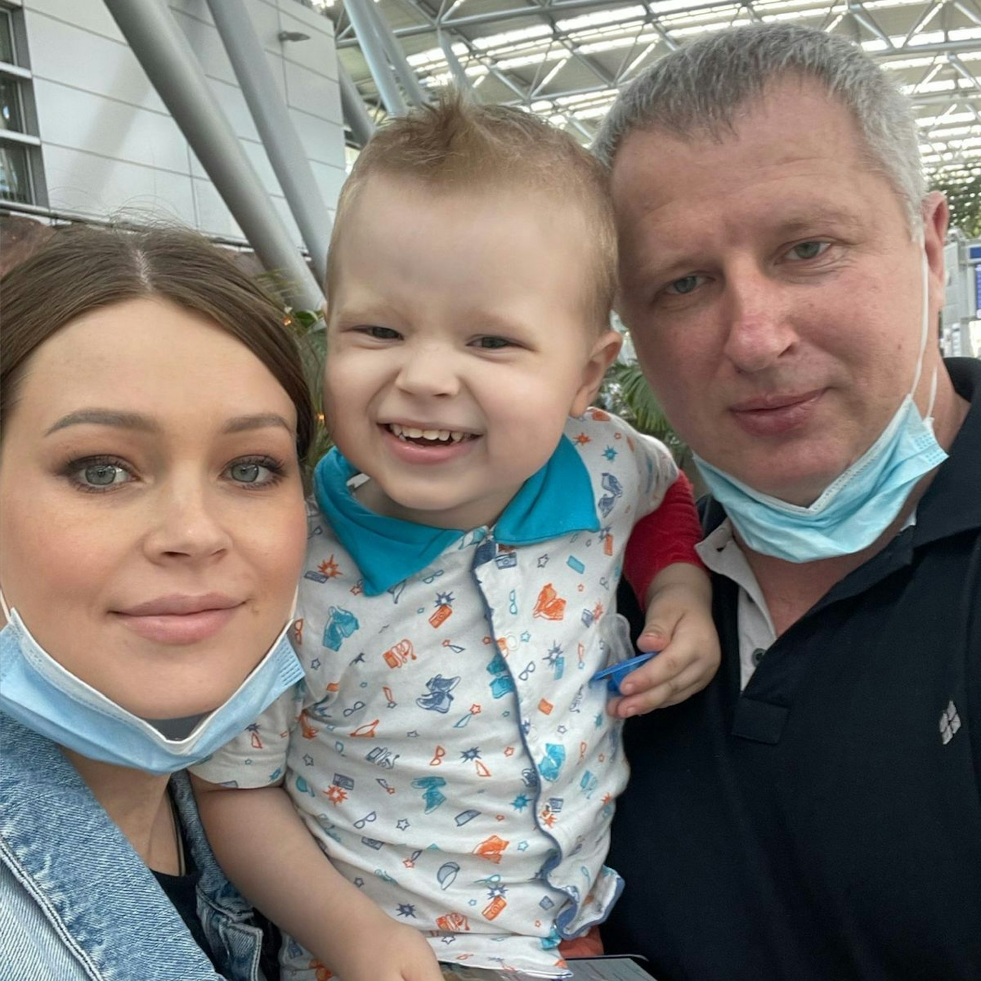 Ein Kind schaut mit seinen Eltern in die Kamera.