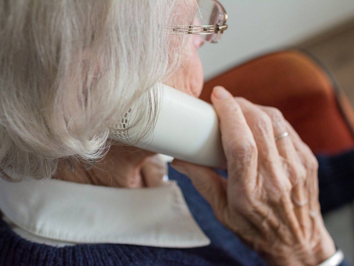 Eine Seniorin mit einem Telefonhörer am Ohr.