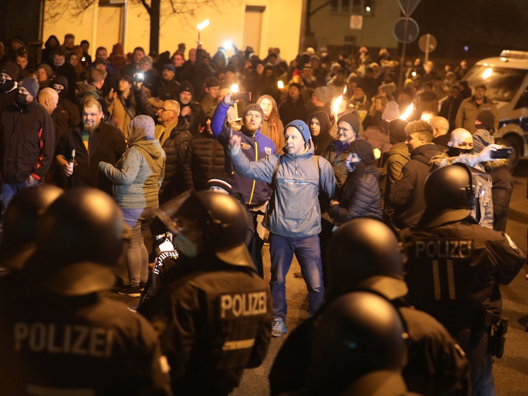 Polizisten und Teilnehmer eines so genannten Spaziergangs gegen die Corona-Maßnahmen stehen sich am 11.12.2021 in Greiz in Thüringen gegenüber.