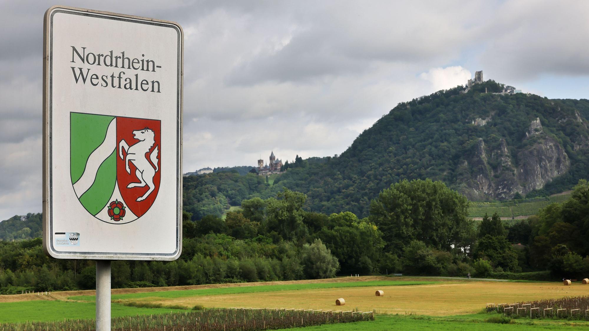 Ein Strassenschild mit dem Landeswappen steht an der Grenze zwischen Nordrhein-Westfalen und Rheinland-Pfalz vor der Kulisse des Drachenfelses.