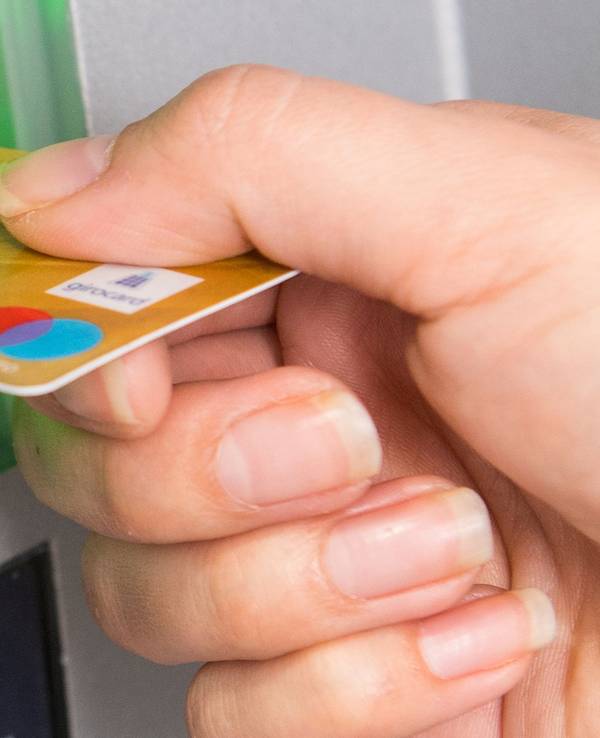 Kunden der Direktbanken ING und 1822direkt müssen ab 2022 Gebühren für ihre Girocard bezahlen. Das Foto zeigt eine Frau, die ihre Girocard in einen Geldautomaten schiebt.