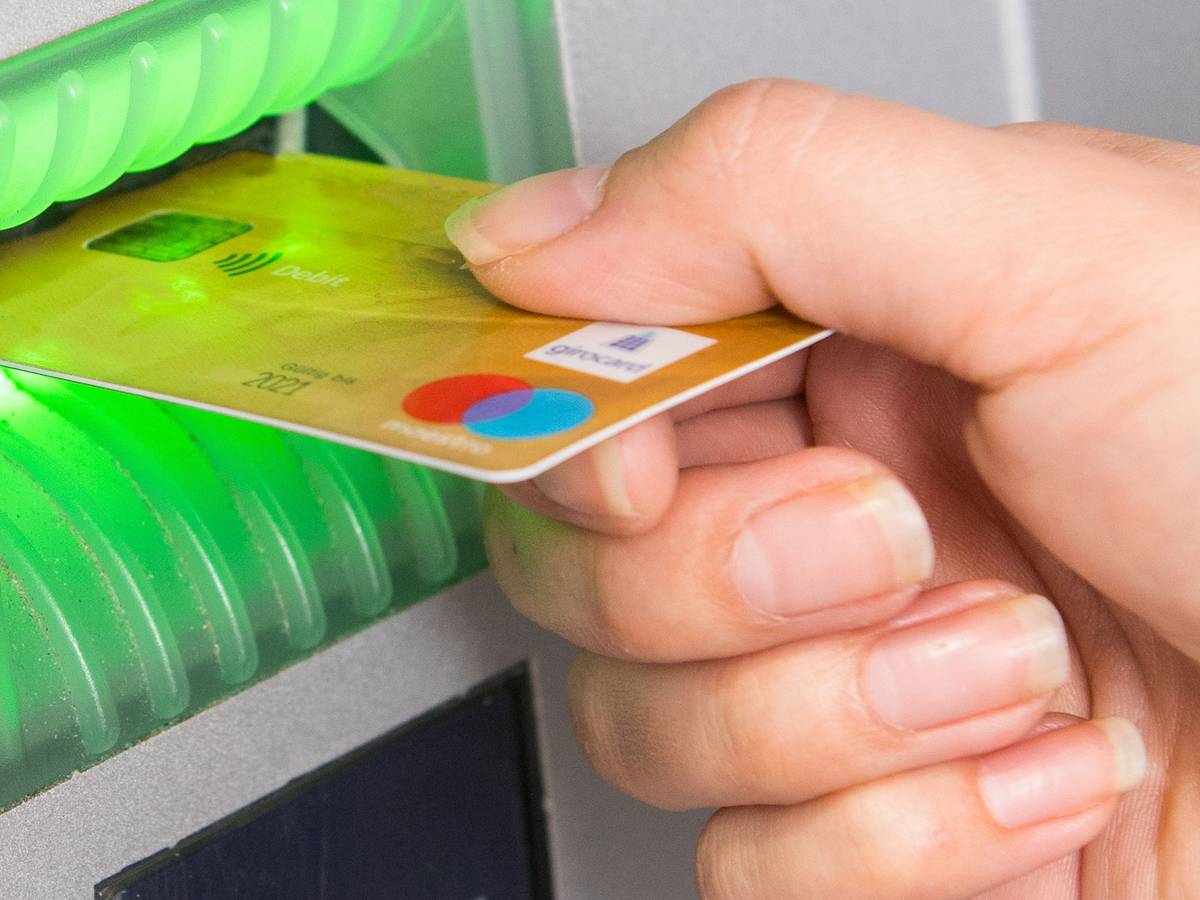 Kunden der Direktbanken ING und 1822direkt müssen ab 2022 Gebühren für ihre Girocard bezahlen. Das Foto zeigt eine Frau, die ihre Girocard in einen Geldautomaten schiebt.