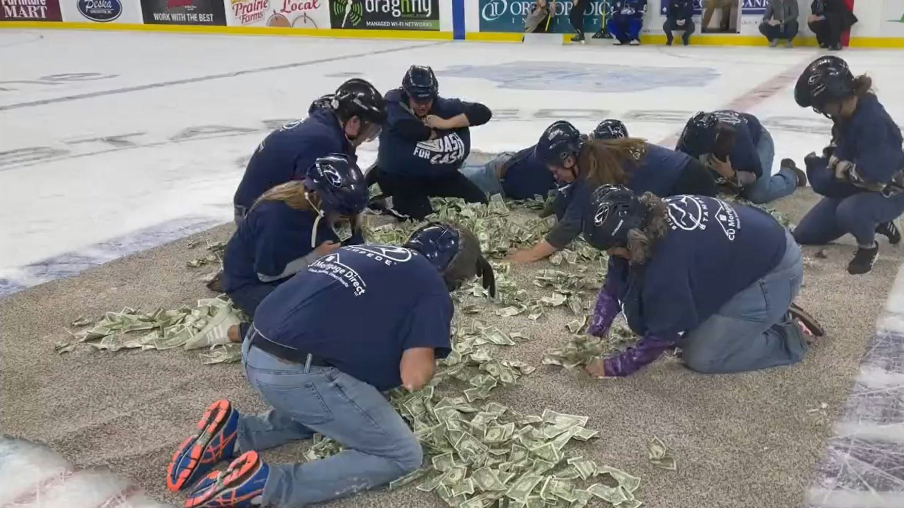 Bei einem Eishockey-Spiel sammeln Lehrer auf Knie Geldscheine auf.