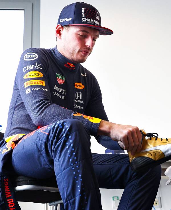 Max Verstappen zieht sich seine neuen goldenen Schuhe an.