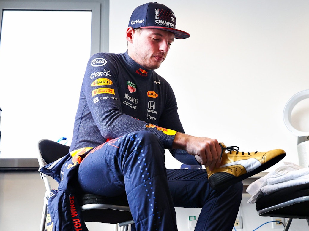 Max Verstappen zieht sich seine neuen goldenen Schuhe an.