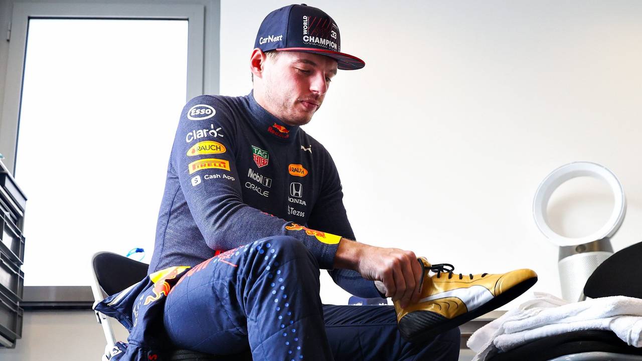 Max Verstappen zieht sich seine neuen goldenen Schuhe an.