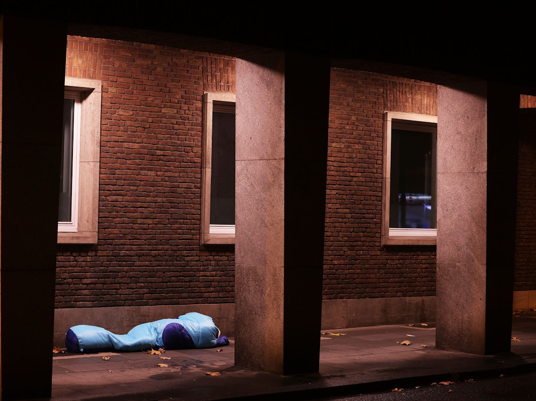 Ein Obdachloser liegt unter einer Überdachung in einer Passage.