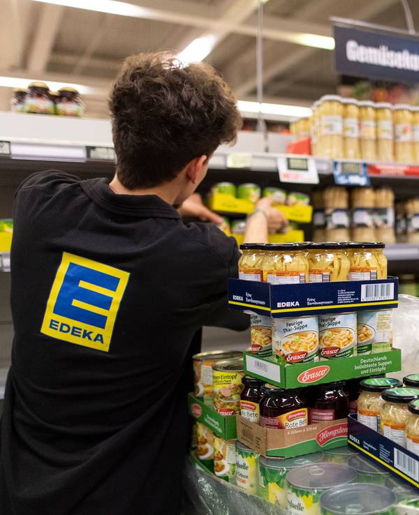 Ein Mitarbeiter von Edeka füllt ein Regal auf.