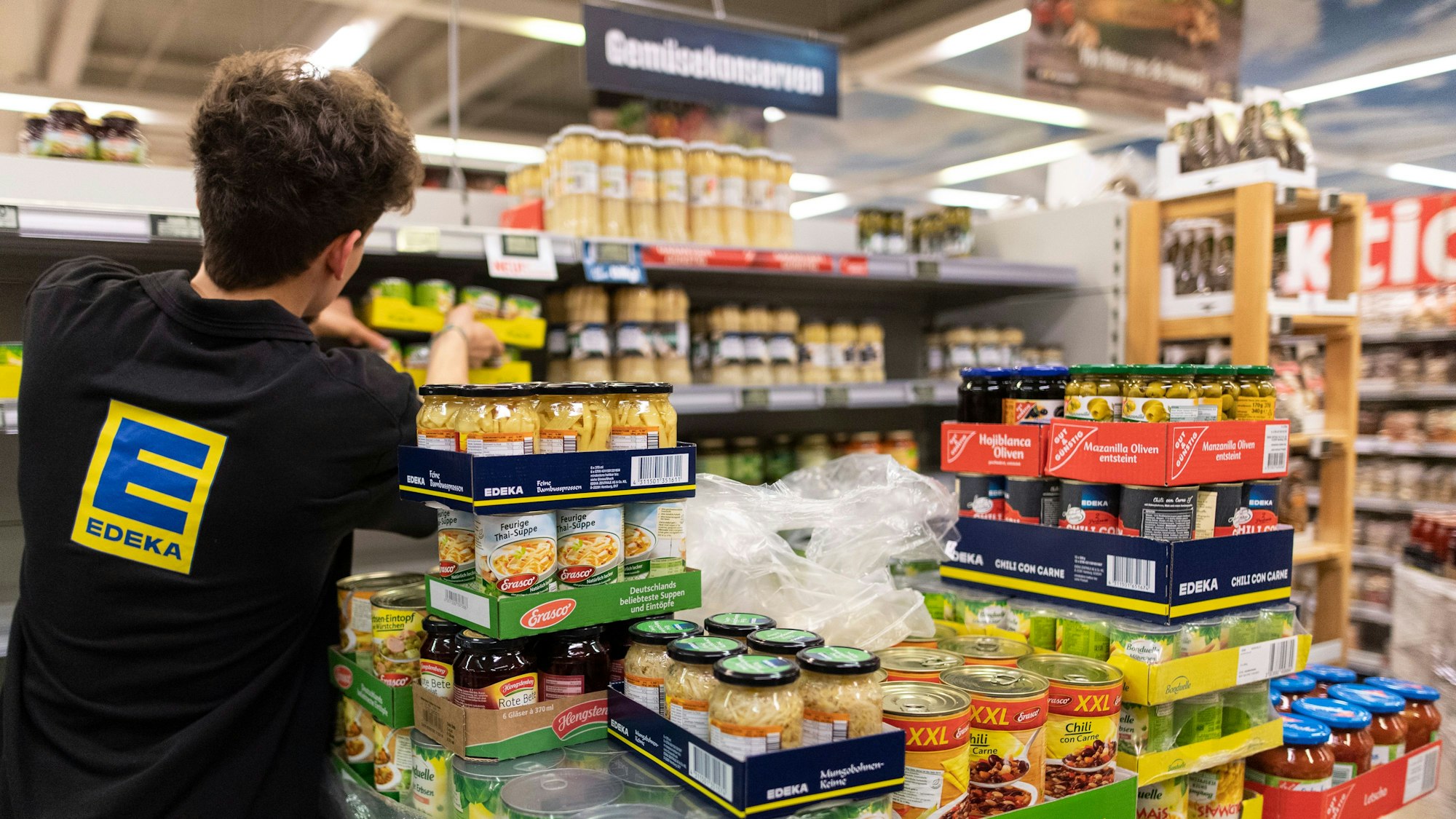 Edeka macht auf den Klimawandel aufmerksam. Hier ein Mitarbeiter, der in einer Filiale Regale einräumt.