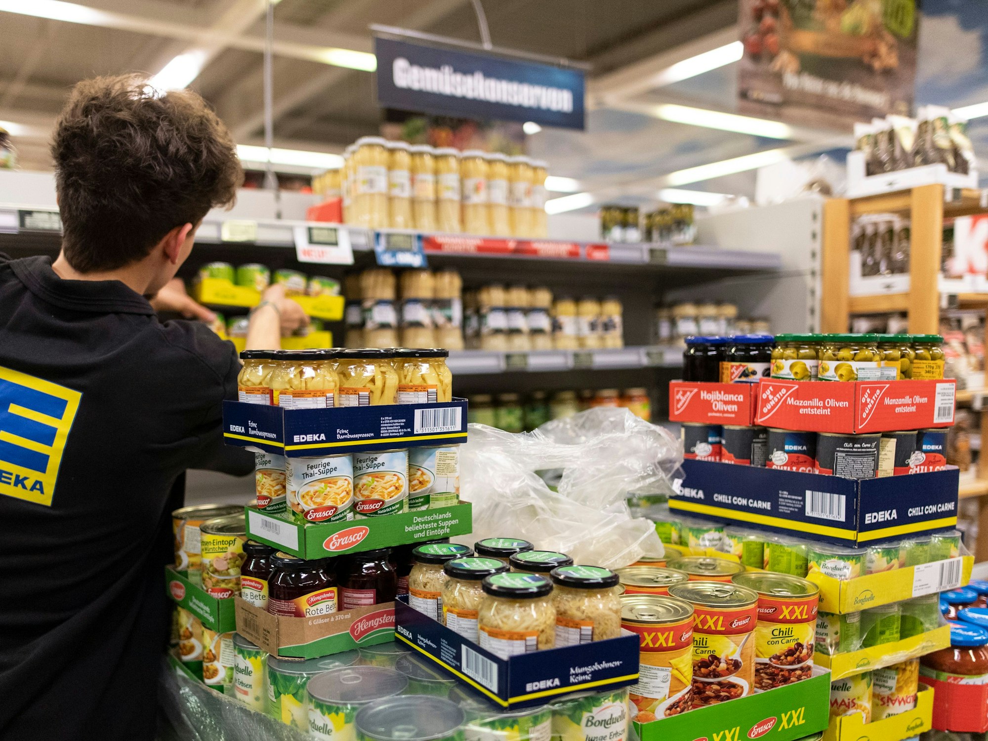 Ein Mitarbeiter von Edeka füllt ein Regal auf.