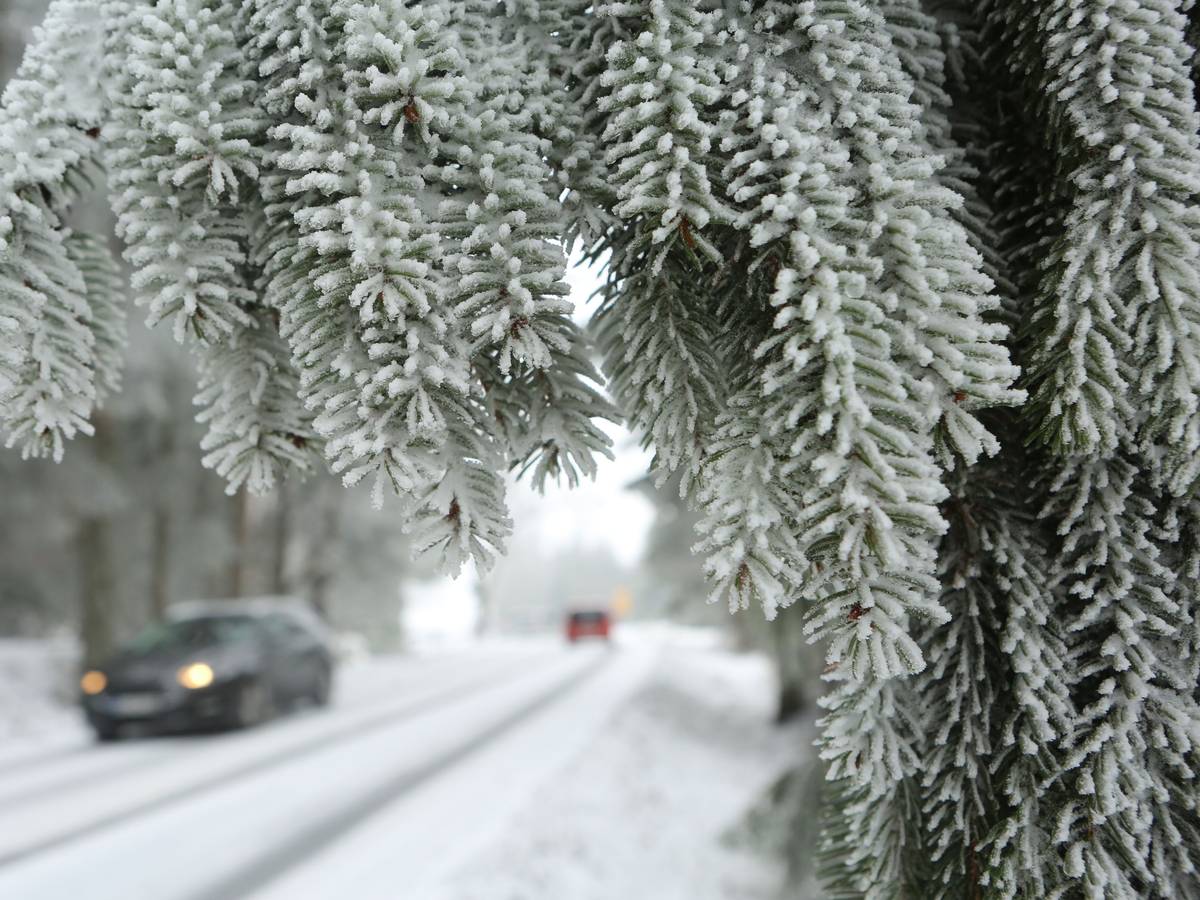 Ein Auto fährt über eine zugeschneite Straße.