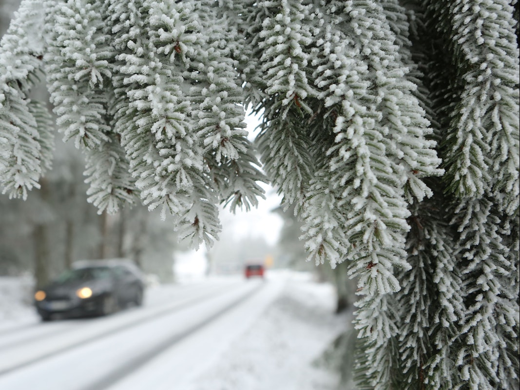 Ein Auto fährt über eine zugeschneite Straße.