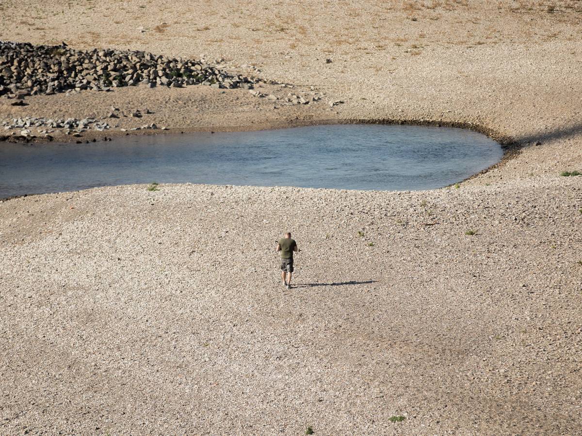 Ein Mann geht am 15. Oktober 2018 bei Niedrigwasser am Rhein entlang. Auch in diesem Jahr hatte der Rhein wieder extremes Niedrigwasser. Ereignisse wie dieses häufen sich in der Klimakrise.