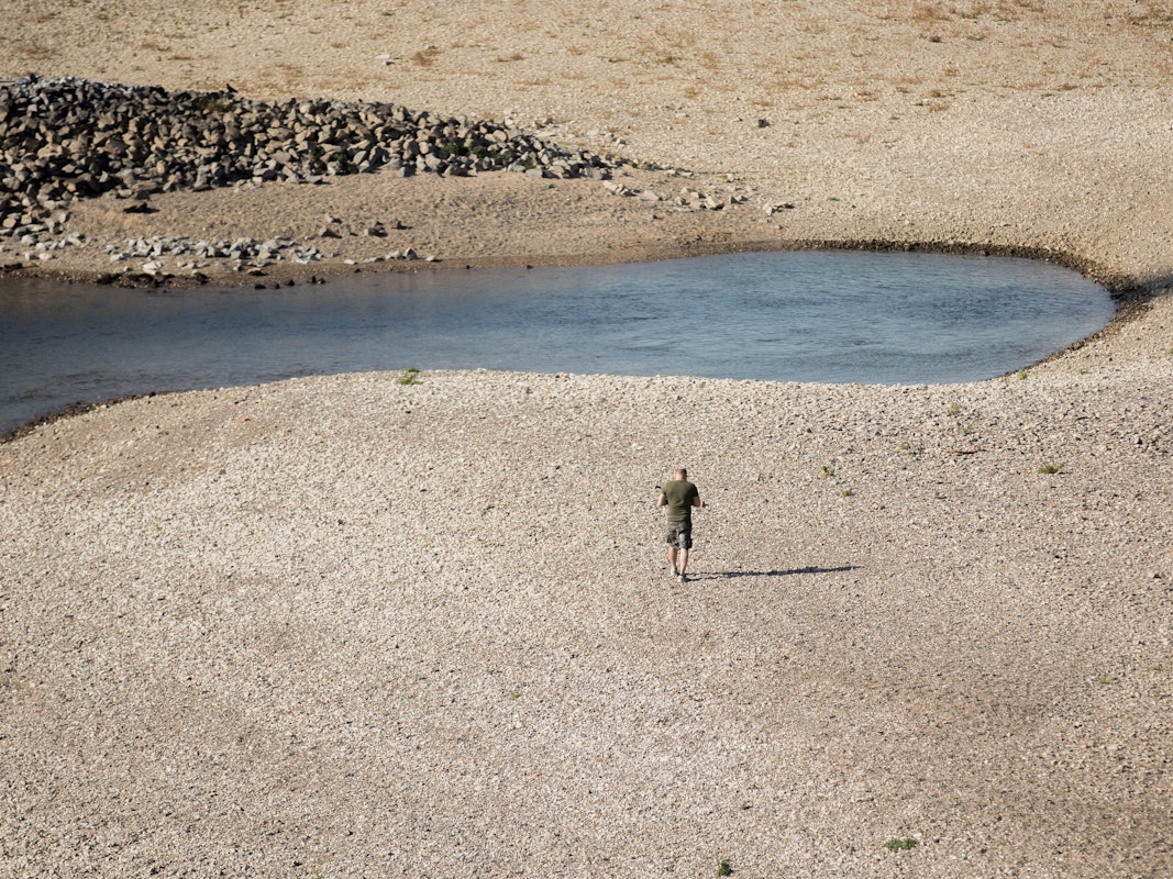Ein Mann geht am 15. Oktober 2018 bei Niedrigwasser am Rhein entlang. Auch in diesem Jahr hatte der Rhein wieder extremes Niedrigwasser. Ereignisse wie dieses häufen sich in der Klimakrise.