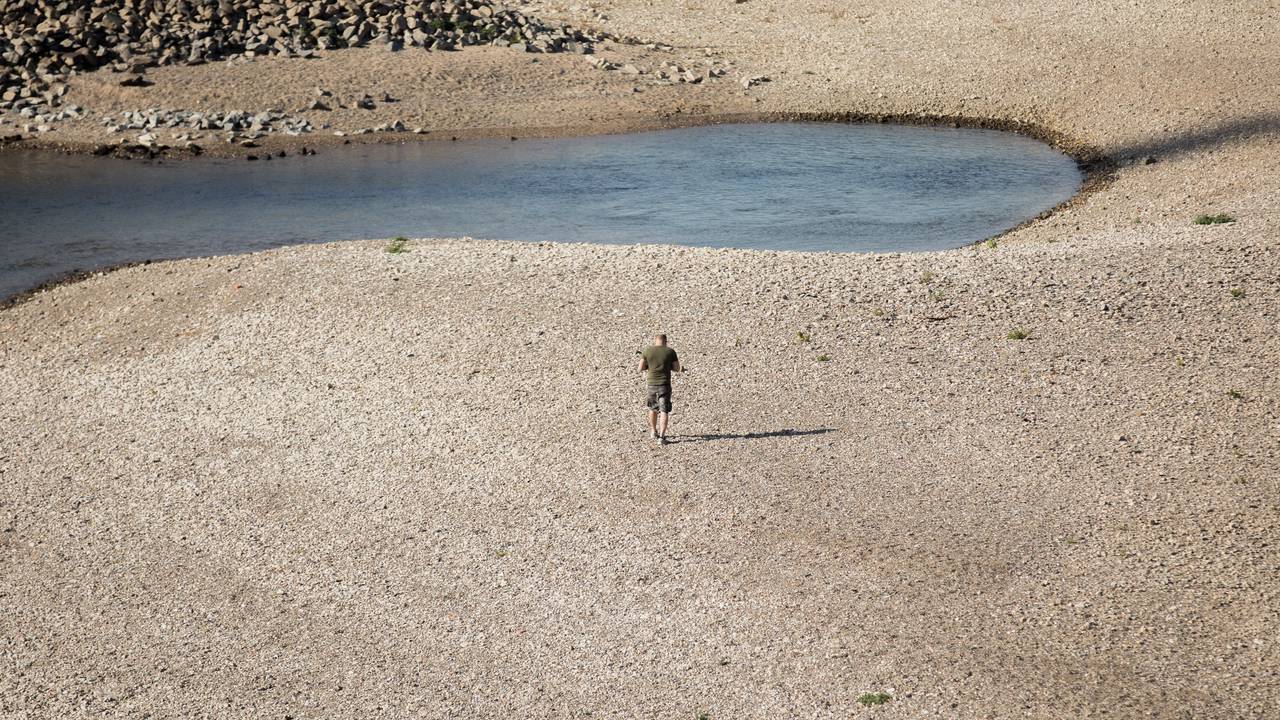 Ein Mann geht am 15. Oktober 2018 bei Niedrigwasser am Rhein entlang. Auch in diesem Jahr hatte der Rhein wieder extremes Niedrigwasser. Ereignisse wie dieses häufen sich in der Klimakrise.