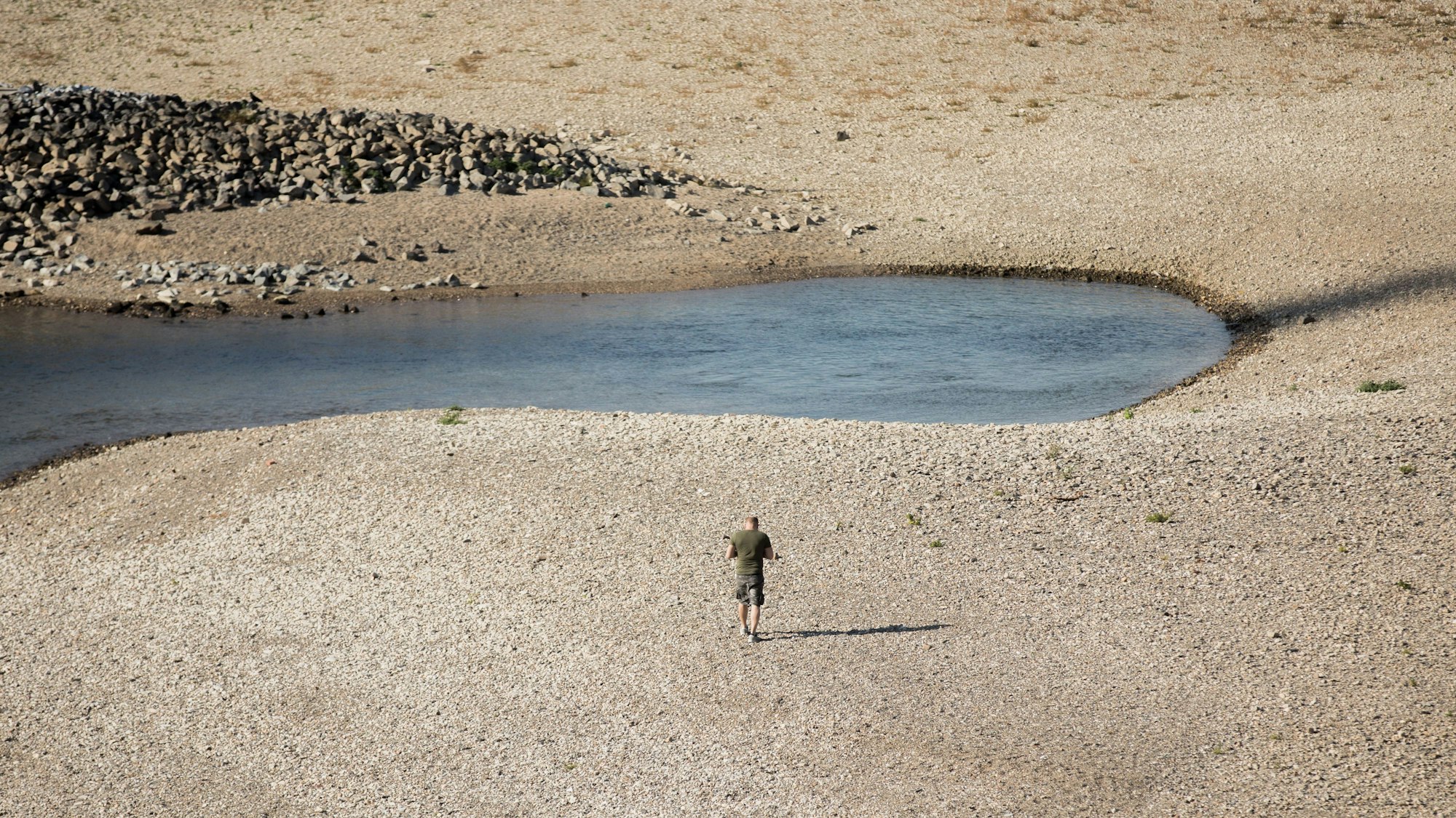 Ein Mann geht am 15. Oktober 2018 bei Niedrigwasser am Rhein entlang. Starkregen und ein Dürresommer, Unwetter und ein ausgetrockneter Rhein - das Wetter in Nordrhein-Westfalen schlägt in diesem Jahr Kapriolen.