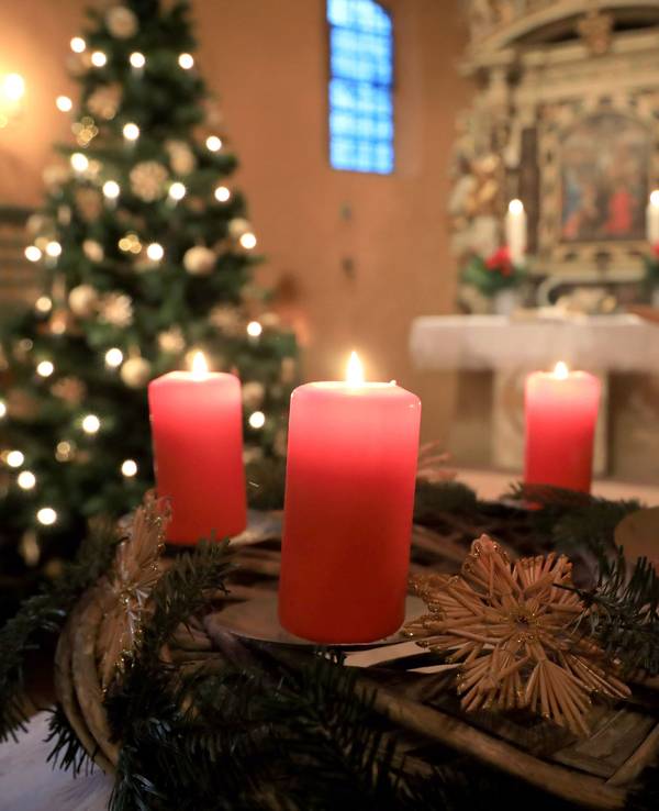 Ein Adventskranz steht beim Gottesdienst vor einem Altar.