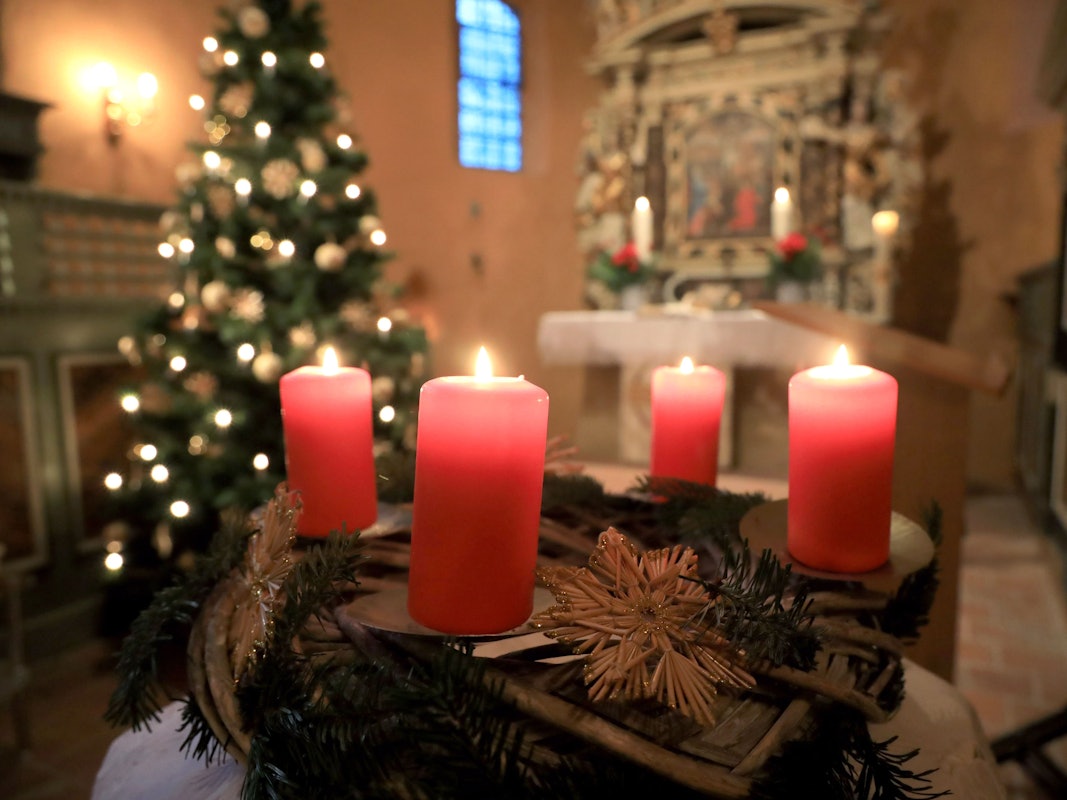 Ein Adventskranz steht beim Gottesdienst vor einem Altar.