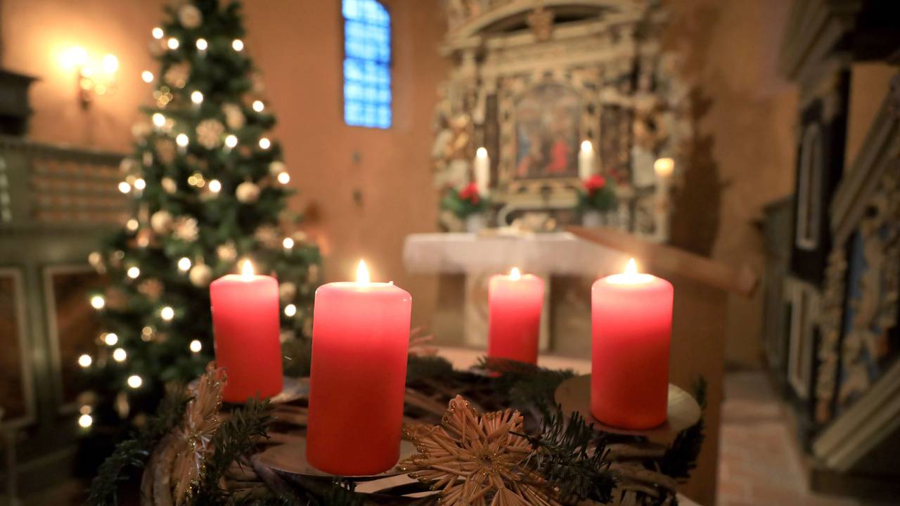 Ein Adventskranz steht beim Gottesdienst vor einem Altar.