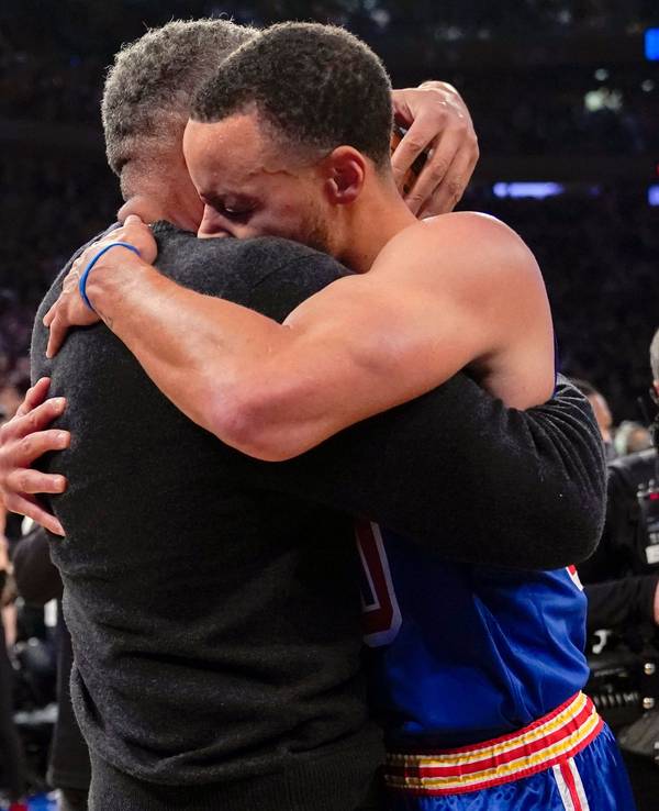 Stephen Curry umarmt seinen Vater Dell Curry am Rand des Spielfelds.