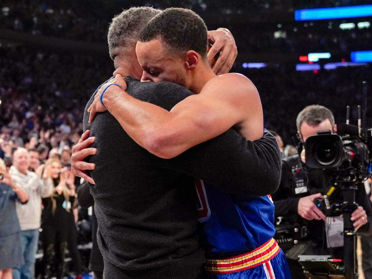 Stephen Curry umarmt seinen Vater Dell Curry am Rand des Spielfelds.