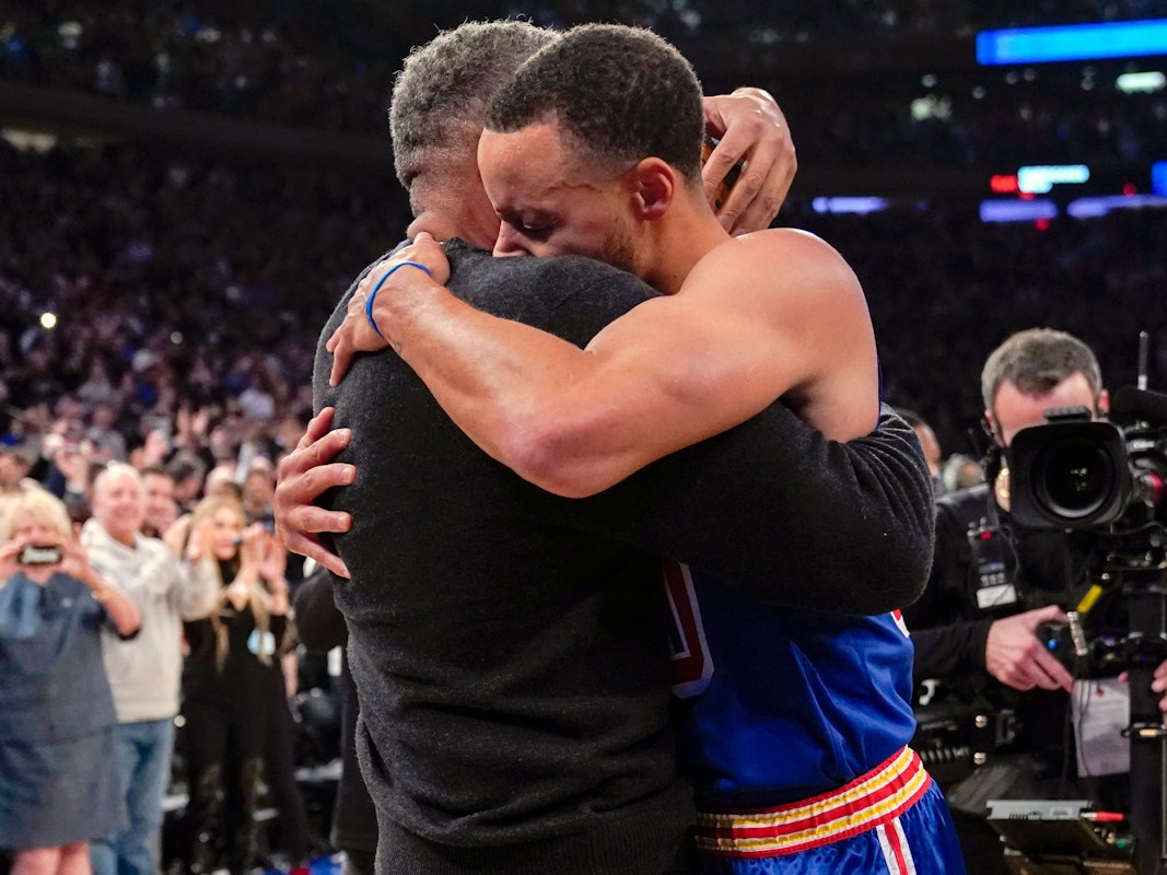 Stephen Curry umarmt seinen Vater Dell Curry am Rand des Spielfelds.