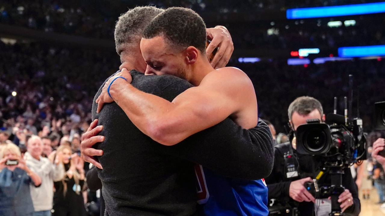 Stephen Curry umarmt seinen Vater Dell Curry am Rand des Spielfelds.