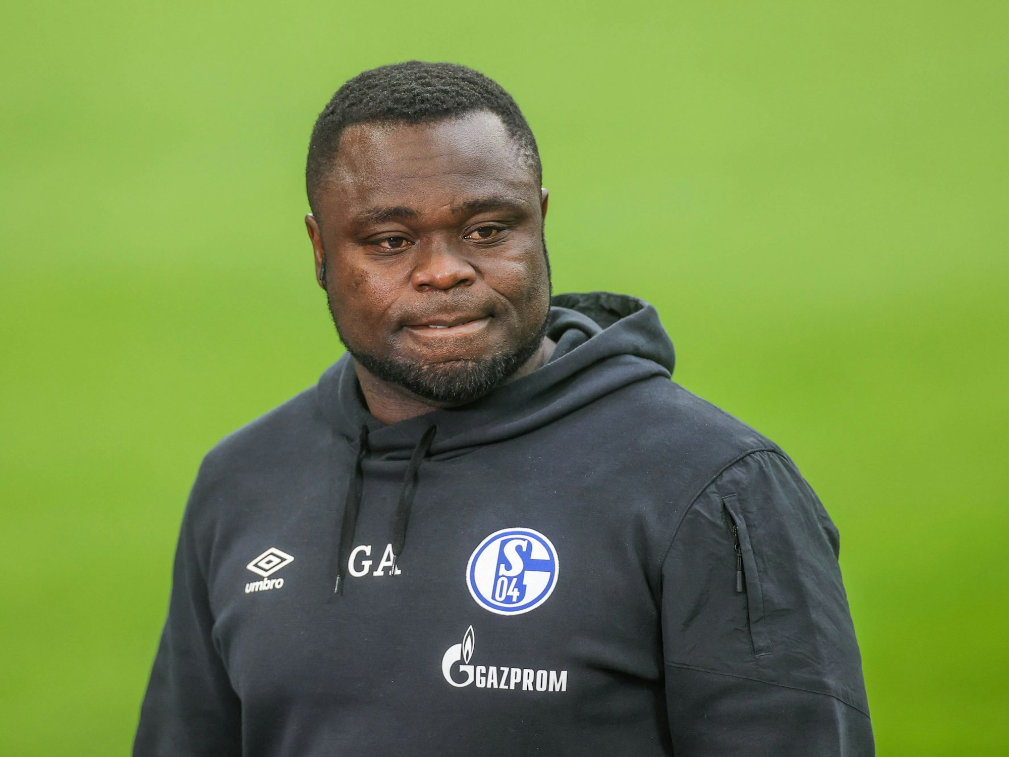 Gerald Asamoah steht im Schalke-Hoodie auf dem Platz.