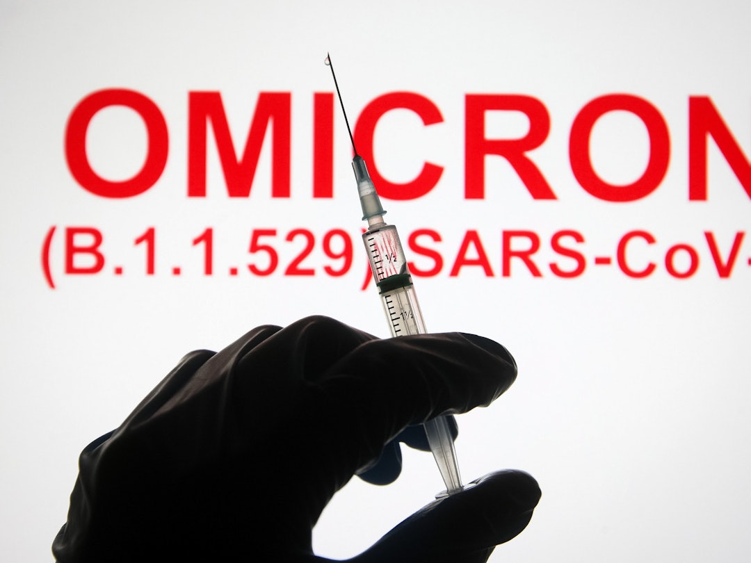 Eine Hand hält vor der Aufschrift „Omicron (B.1.1.529): SARS-CoV-2“ eine Spritze hoch.
