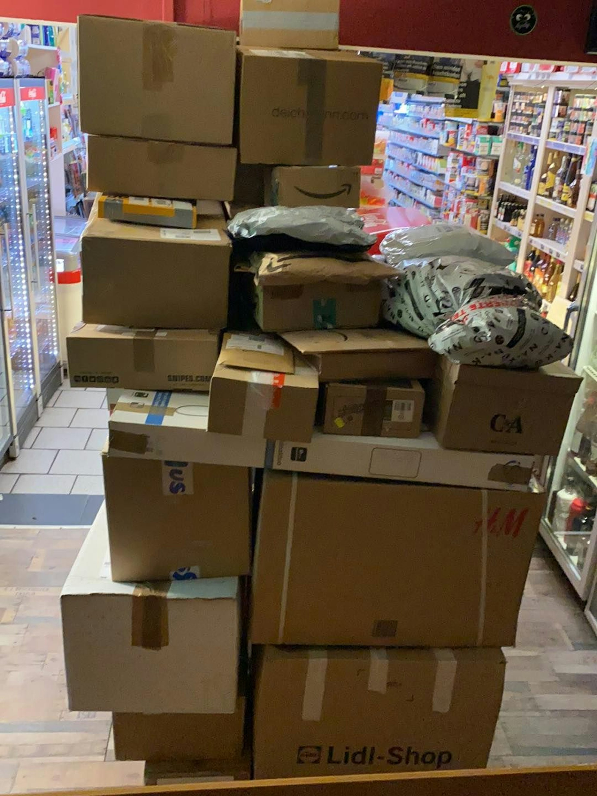 Pakete stehen gestapelt in einem Kiosk.