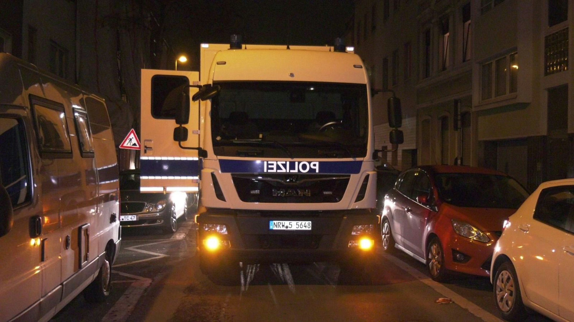 Ein Polizeifahrzeug steht auf einer Straße, eine Tür ist geöffnet.