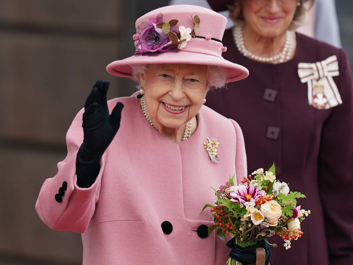 Die britische Königin Elizabeth II. hält einen Blumenstrauß in der Hand und winkt, nachdem sie nach der Eröffnungszeremonie des walisischen Parlaments das Parlamentsgebäude verlässt.