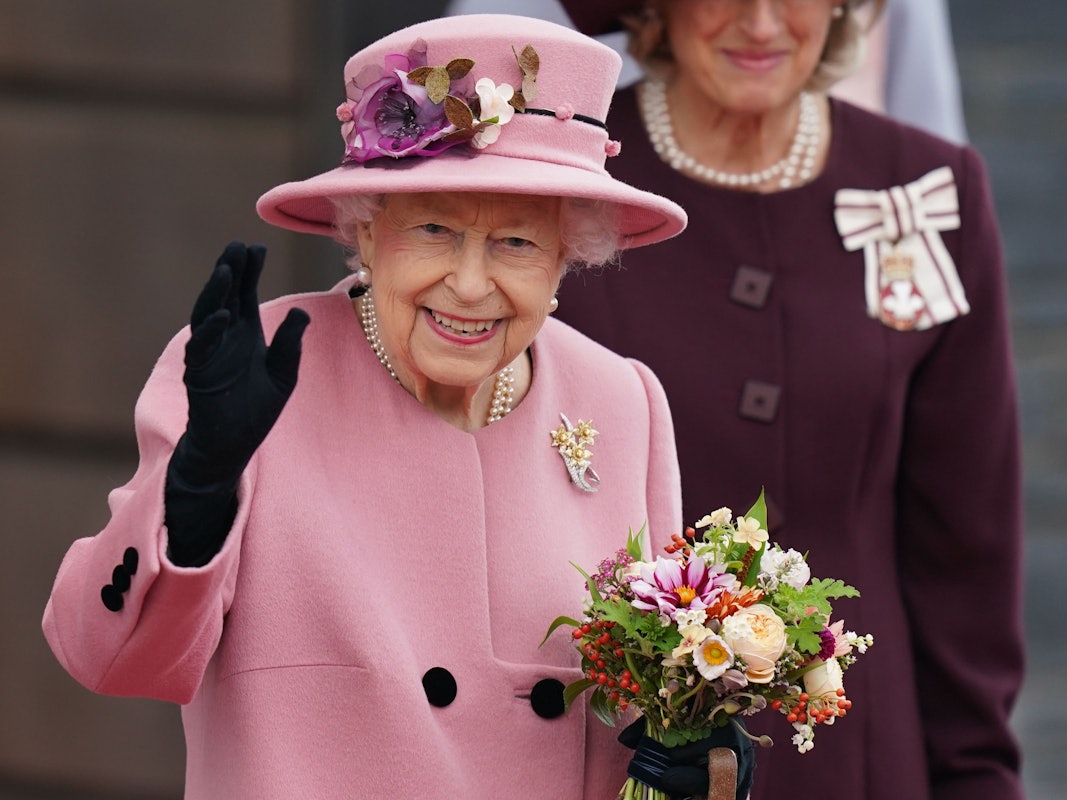 Die britische Königin Elizabeth II. hält einen Blumenstrauß in der Hand und winkt, nachdem sie nach der Eröffnungszeremonie des walisischen Parlaments das Parlamentsgebäude verlässt.