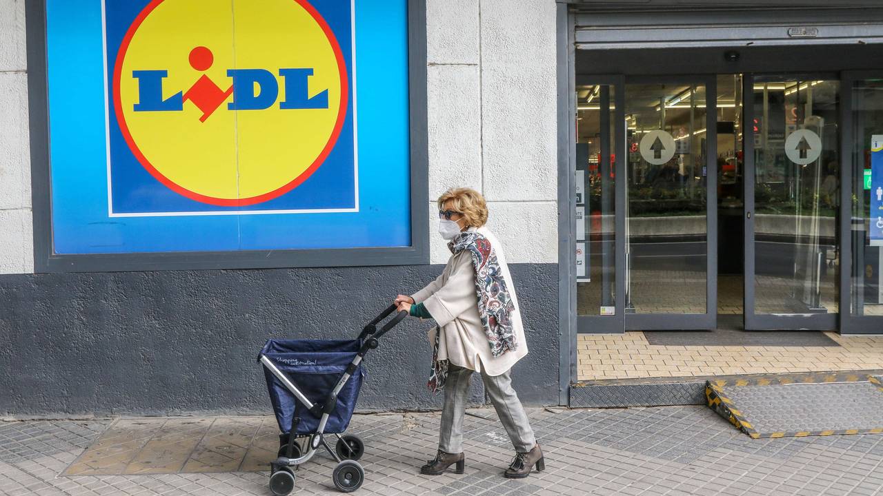Eine Frau mit Rollator trägt einen Mund-Nasen-Schutz und passiert einen Lidl.