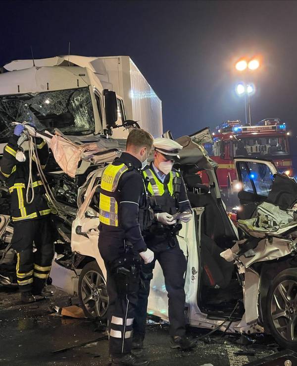 Polizisten stehen nach einem schweren Unfall an einem zerstörten Fahrzeug.