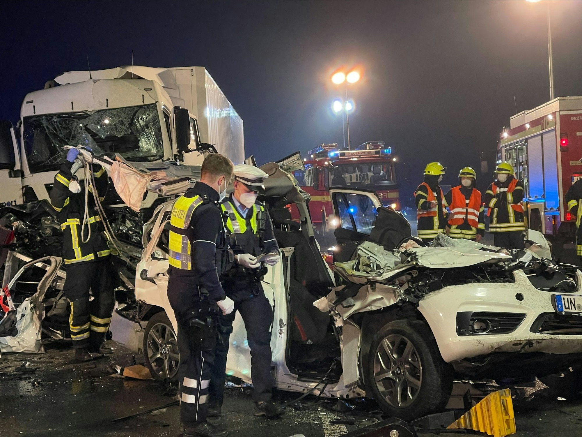Polizisten stehen nach einem schweren Unfall auf der Autobahn 1 an einem zerstörten Fahrzeug.