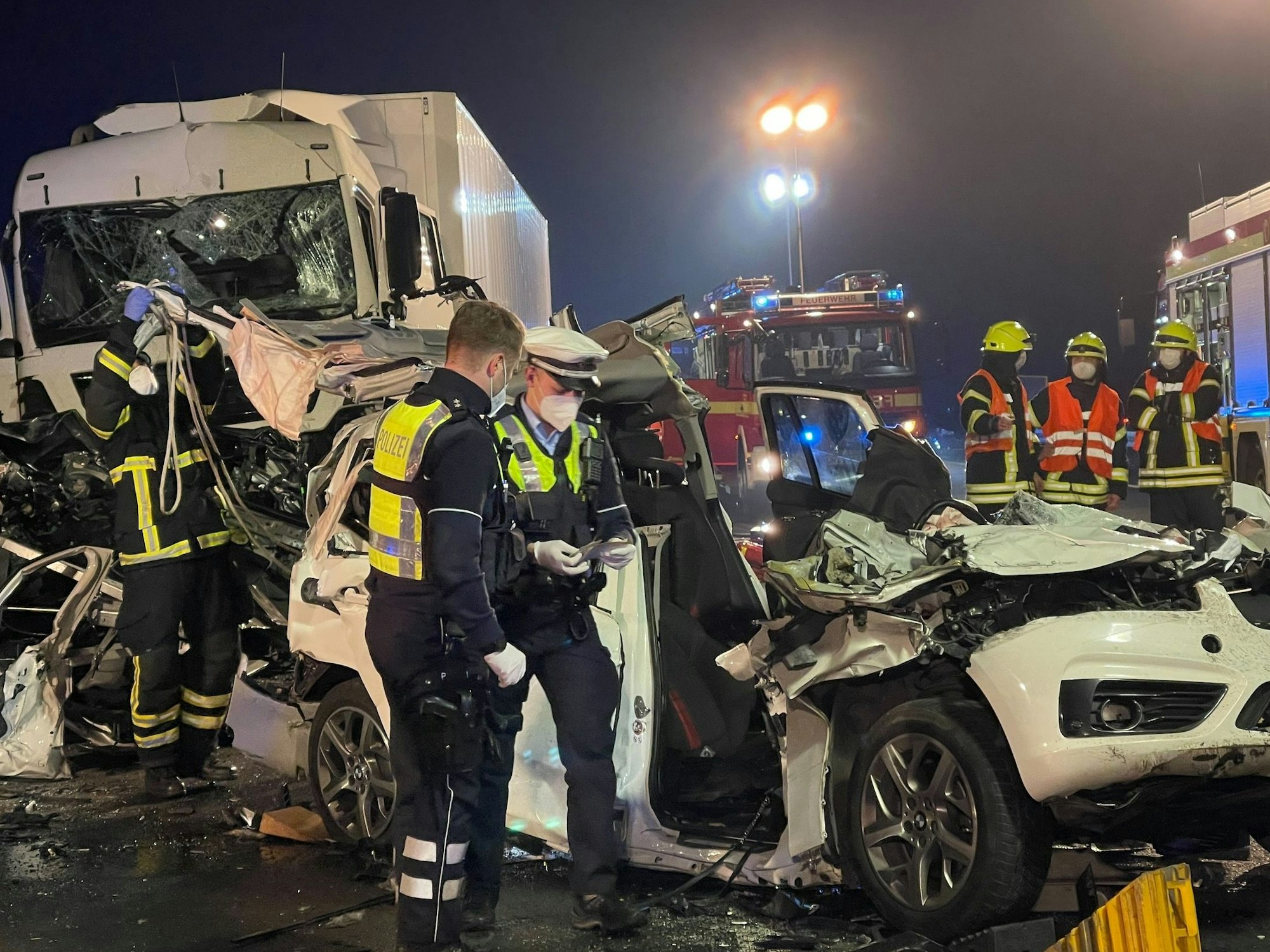 Polizisten stehen nach einem schweren Unfall an einem zerstörten Fahrzeug.