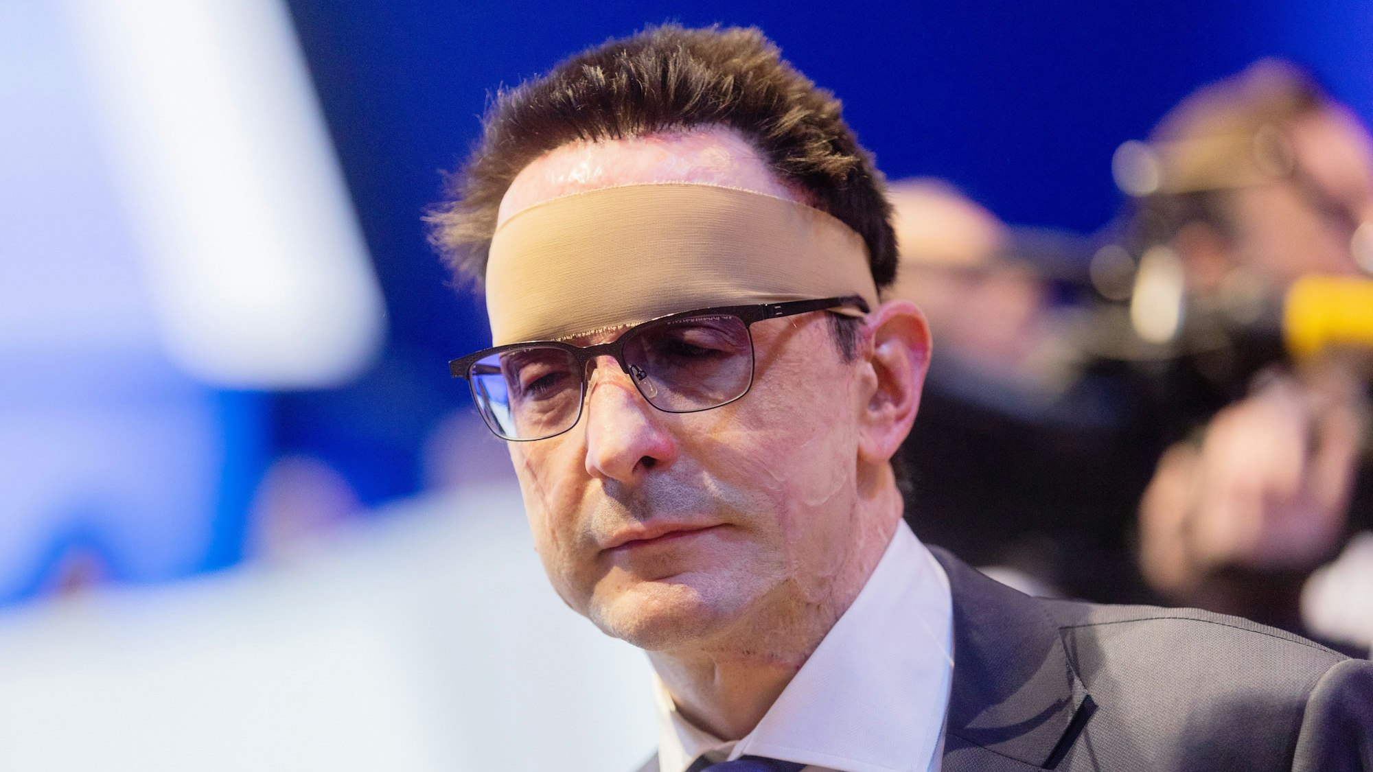 Bernhard Günther steht mit Verband um den Kopf in einem Raum.