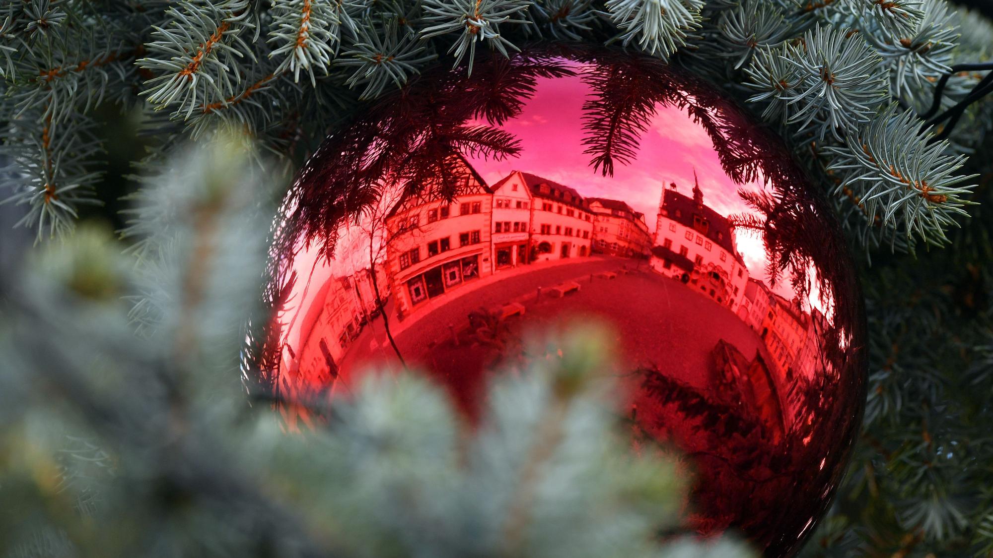 Eine rote Christbaumkugel hängt an einem Weihnachtsbaum.