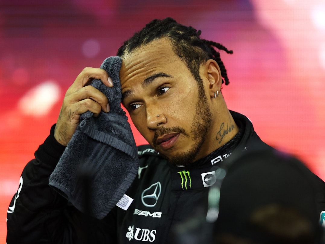 Lewis Hamilton wischt sich den Schweiß von der Stirn.