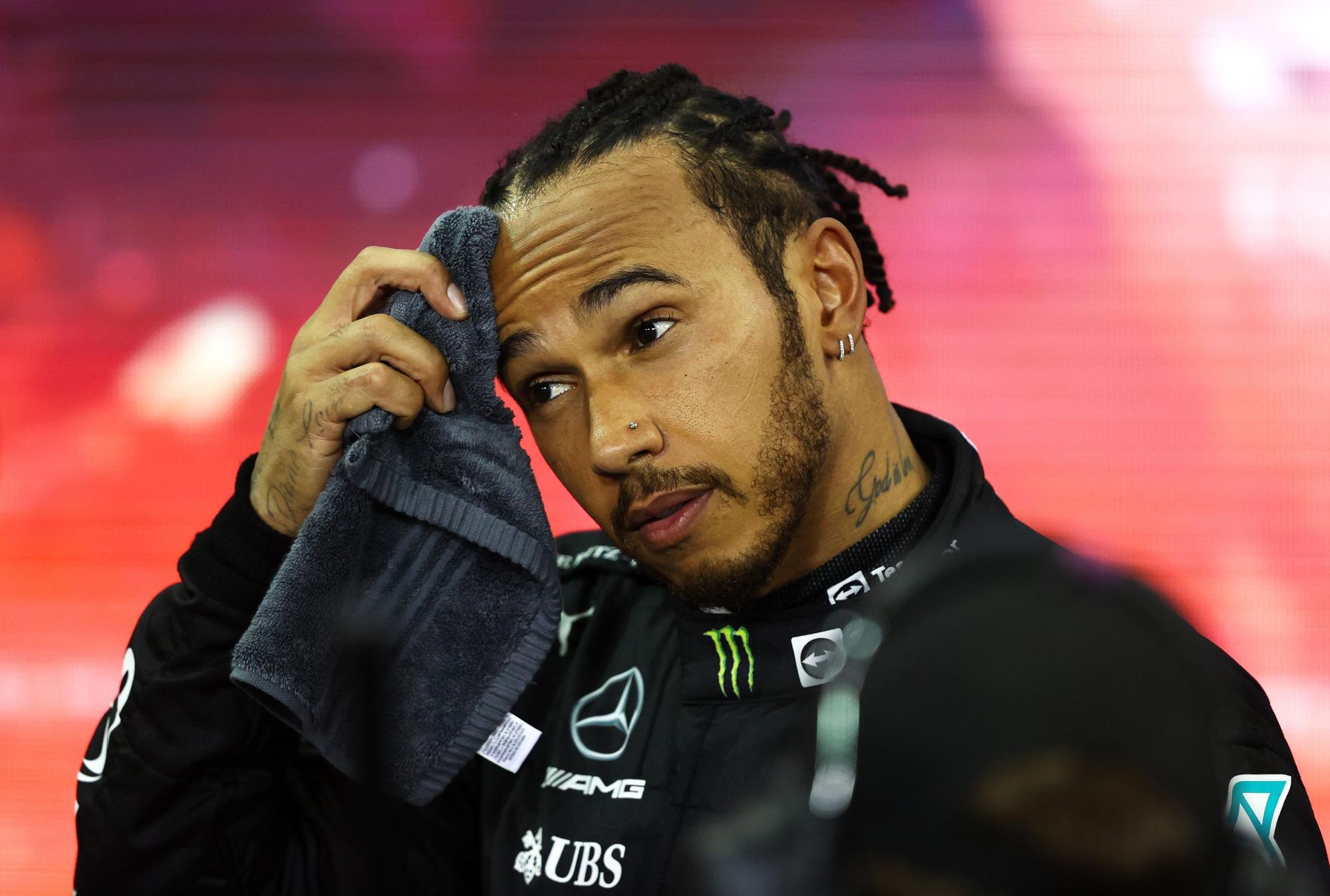 Lewis Hamilton wischt sich den Schweiß von der Stirn.