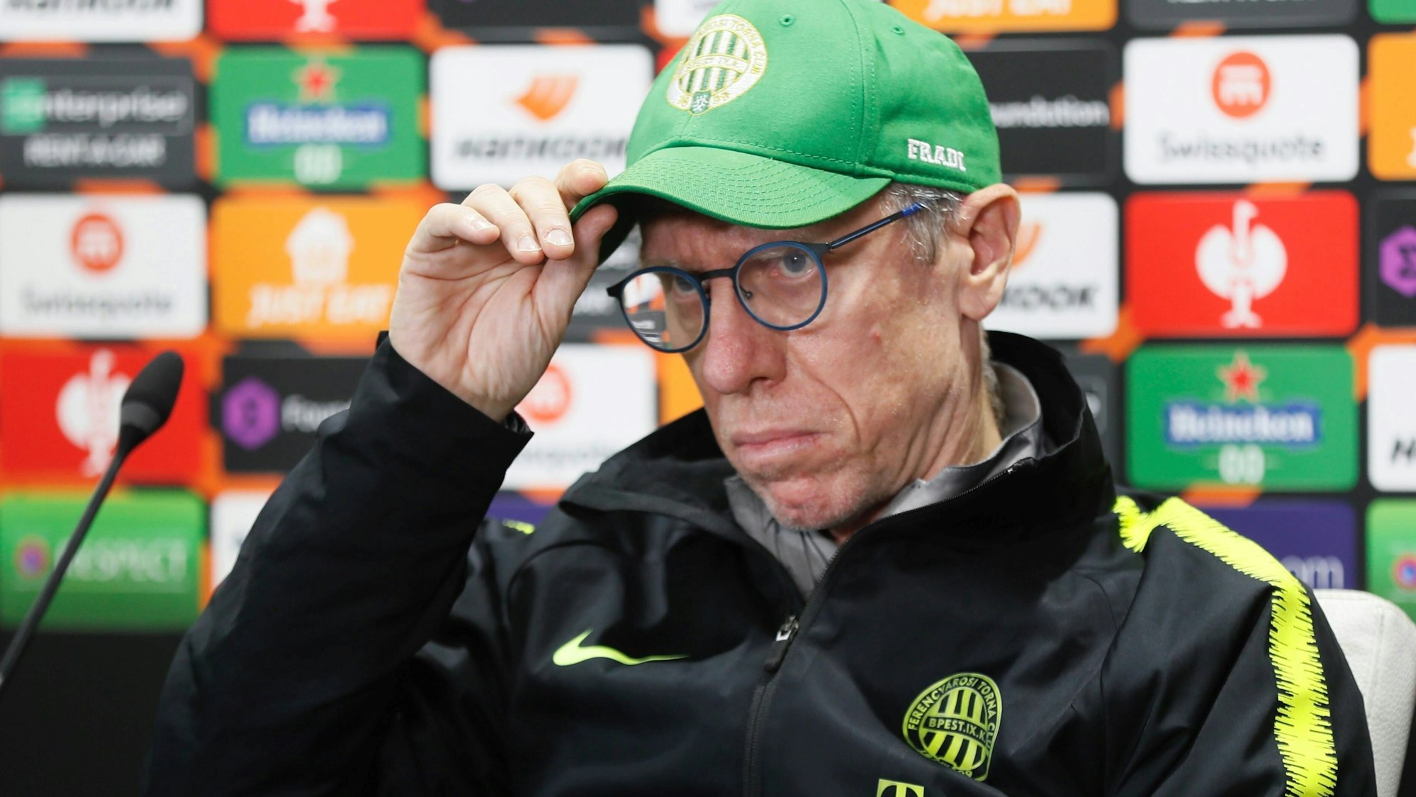 Peter Stöger sitzt bei einer Pressekonferenz von Ferencvaros Budapest.