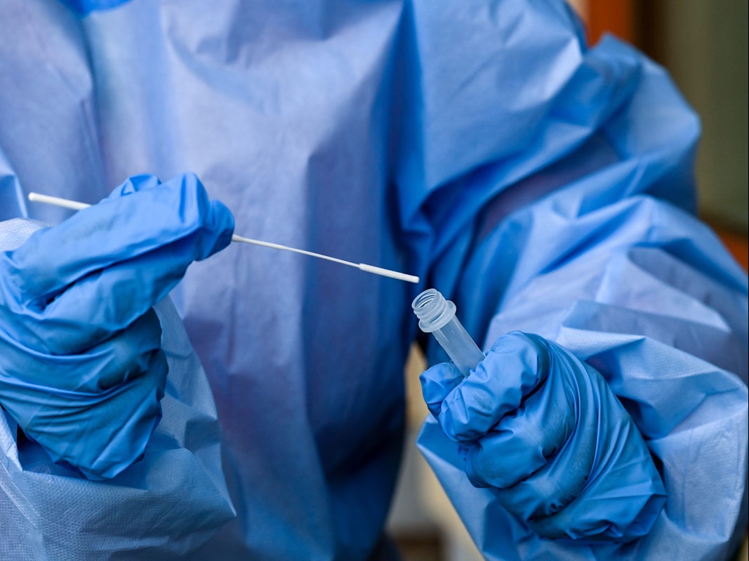 Eine Krankenschwester eines mobilen Test-Teams des Deutschen Roten Kreuzes (DRK) steckt während einer Corona-Testung am 8. November 2021 ein Teststäbchen in die Flüssigkeit eines Schnelltests in einer Seniorenbetreuungseinrichtung. Das Symbolfoto wurde in Zossen (Brandenburg) aufgenommen.