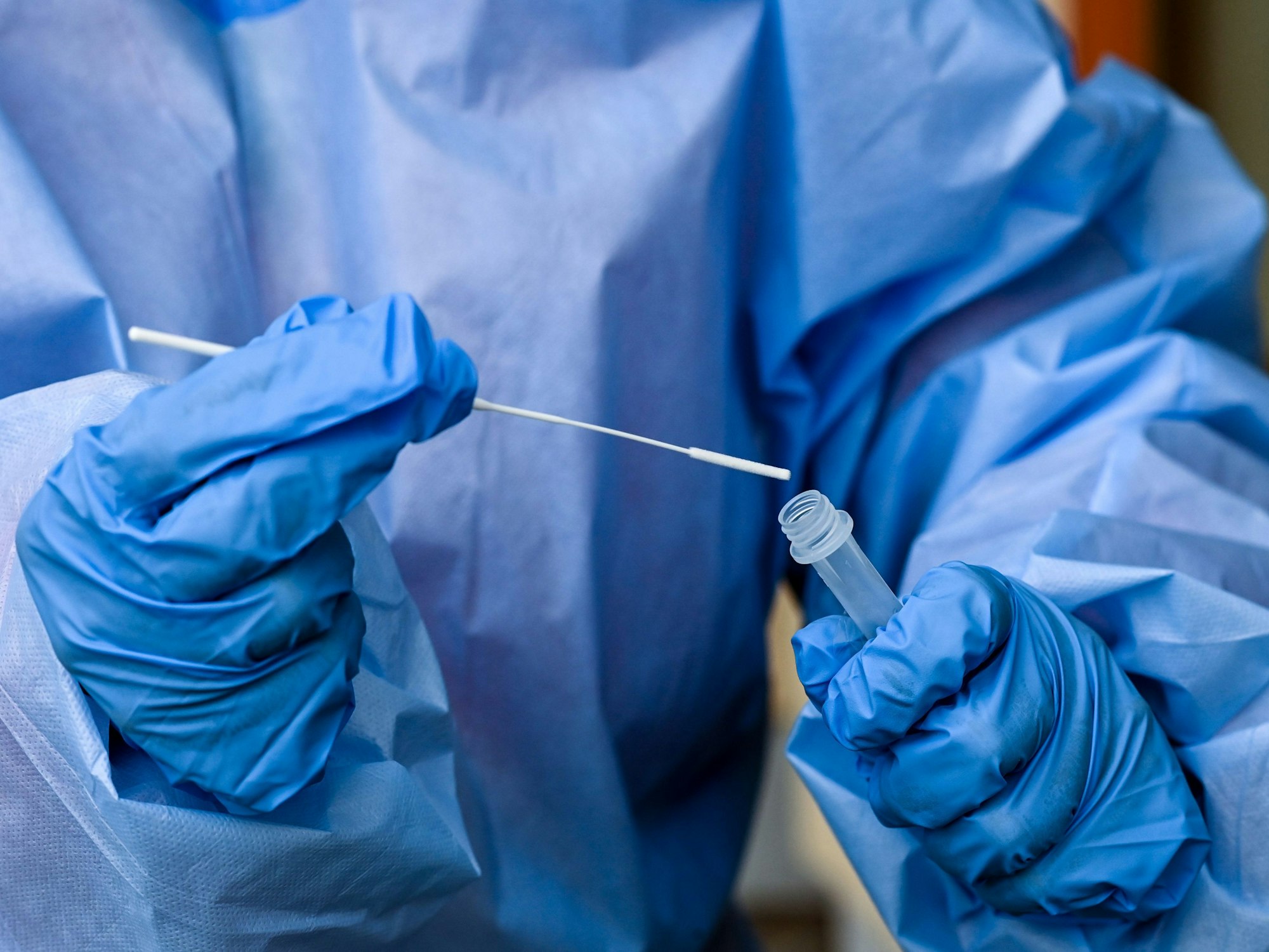 Eine Krankenschwester eines mobilen Test-Teams des Deutschen Roten Kreuzes (DRK) steckt während einer Corona-Testung am 8. November 2021 ein Teststäbchen in die Flüssigkeit eines Schnelltests in einer Seniorenbetreuungseinrichtung. Das Symbolfoto wurde in Zossen (Brandenburg) aufgenommen.