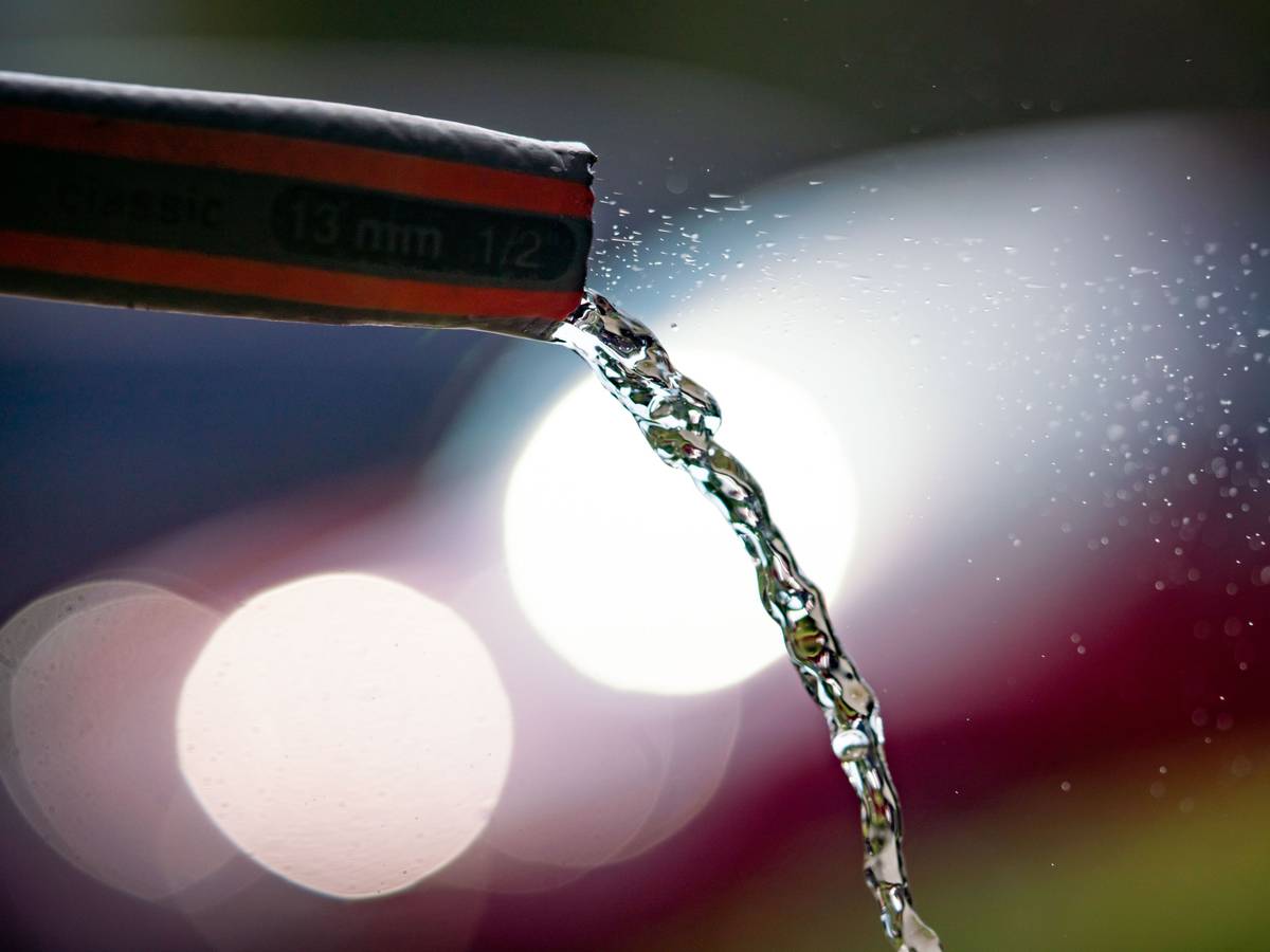 Wasser fließt in einem Frankfurter Vorgarten aus einem Gartenschlauch.